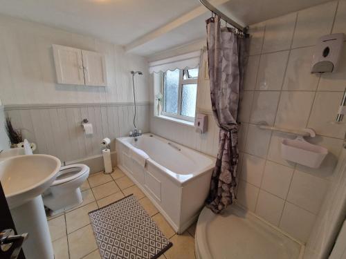 a bathroom with a tub and a toilet and a sink at 4 Bedroom house in Merthyr Tydfil. Near Brecon Beacons National Park in Dowlais