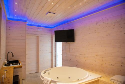 a bathroom with a tub and a tv on the wall at ARTEMIDE "Corte Segreta" B&B SUITE SPA in San Cipriano Picentino