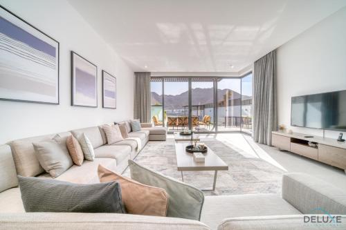 Luxury 4BR Villa with Assistant’s Room Al Dana Island, Fujairah by Deluxe Holiday Homes في الفجيرة: غرفة معيشة مع أريكة وتلفزيون