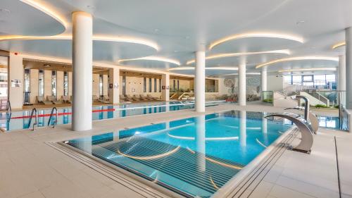 a large swimming pool in a building with columns at Polanki Aqua Nature View in Kołobrzeg