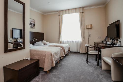 a hotel room with a bed and a desk and a mirror at Hotel Aurora Family & SPA in Międzyzdroje