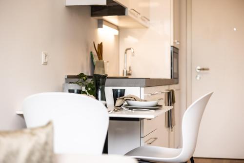 een keuken met een tafel en 2 witte stoelen bij Smart Living Dornbirn in Dornbirn