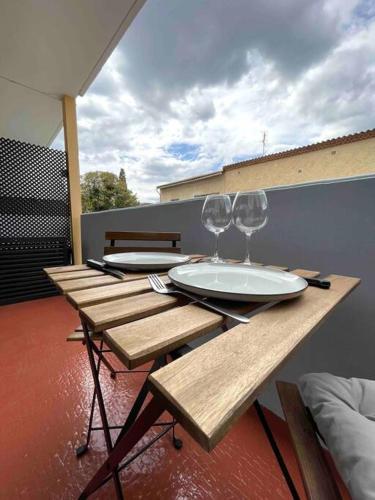 une table en bois avec deux verres à vin dessus dans l'établissement Charmant Studio Beaux Arts avec Clim et terrasse, à Montpellier