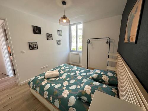 a bedroom with a bed with a green comforter and a window at Appartement JAZZ Vienne nord in Vienne