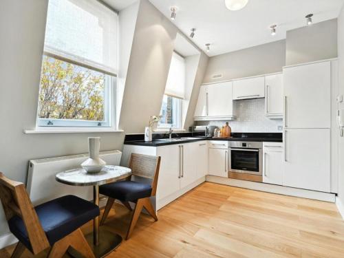 una cucina con armadi bianchi, tavolo e sedie di Mayfair Luxury Apartment Sleeps 6 people a Londra