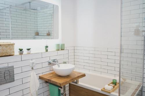uma casa de banho com um lavatório e uma banheira em 80 m2 l Central lWLAN lNetflix l MuYa Apartments em Hanôver