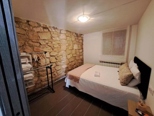 a small room with a bed and a stone wall at Apartamento Clau in Puigmoreno