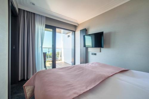 a bedroom with a bed and a large window at Hotel Aurora Family & SPA in Międzyzdroje