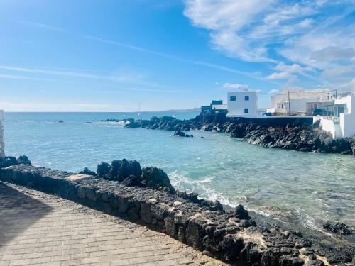 a walkway next to the ocean with rocks and buildings at Canaryislandshost l Cala in Punta de Mujeres