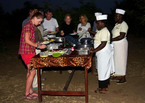 eine Gruppe von Menschen, die um einen Tisch mit Essen stehen in der Unterkunft Euphorbia Safari Lodge in Kasenyi