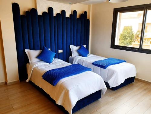 two beds with blue pillows in a room at Incantevole villa Safi Sidi Bouzid near beach in Safi
