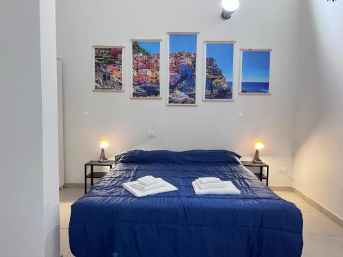 1 dormitorio con 1 cama azul y 4 cuadros en la pared en 8 Lofts - Apartments, en La Spezia