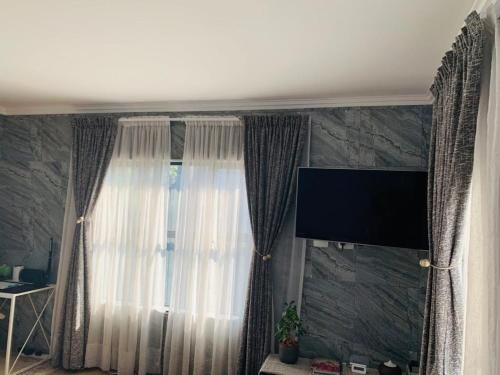 een kamer met een raam met gordijnen en een televisie bij Private Deluxe Bedroom with Backup Power in Johannesburg