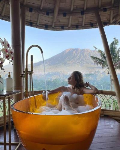 a woman sitting in a bath tub with water at Jiva Bali - Inaya in Selat