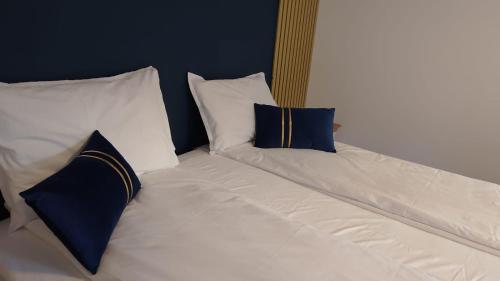 a white bed with two blue pillows on it at Sandnes Central Suite in Sandnes