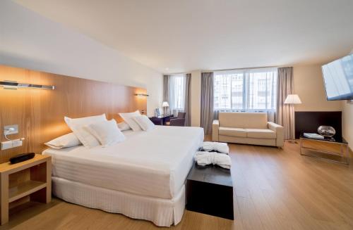 una camera d'albergo con un grande letto bianco e una sedia di Occidental Cádiz a Cadice