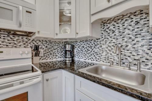 a kitchen with white cabinets and a sink at Hamlet's Passion Beach in Tybee Island