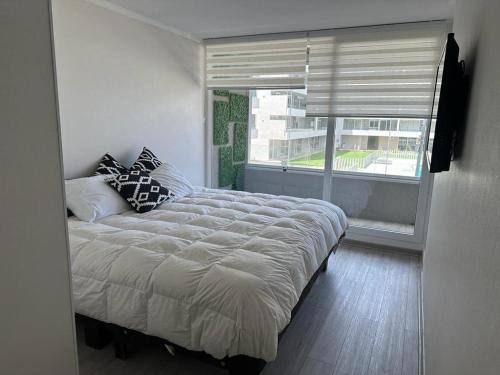 ein Schlafzimmer mit einem großen Bett und einem großen Fenster in der Unterkunft Departamento La Serena in La Serena