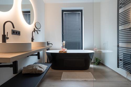 a bathroom with a tub and a sink at NIEUW - De Grenspaal WEST 6P 5 min Maastricht - Sauna - Laadpaal in Riemst