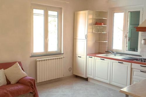 uma cozinha com armários brancos, um lavatório e um sofá em Casa Mariel em La Spezia