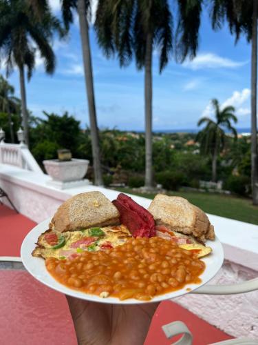 una persona sosteniendo un plato de comida con frijoles en Peaceful Palms Montego Bay en Montego Bay