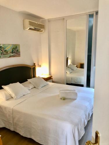 a bedroom with a large white bed and a mirror at Hotel Pinocchio in Cattolica