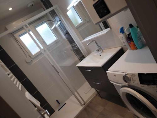 a small bathroom with a shower and a washing machine at Appart6 Pers garage centre à 500m in La Bresse