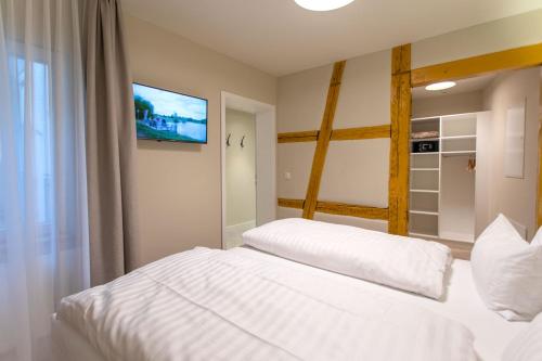 a bedroom with two white beds and a tv at Hotel Tuchhaus in Volkach