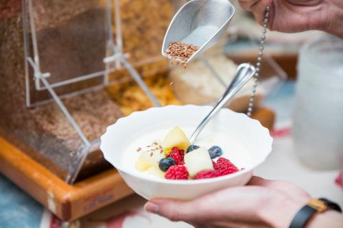 a person holding a bowl of fruit with a spoon at Bergsporthotel Antonie in Gries im Sellrain