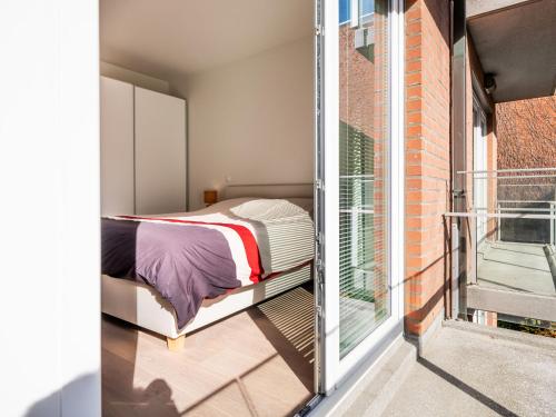 ein Schlafzimmer mit einem Bett neben einem Balkon in der Unterkunft Winoc 302 luxury family apartment on the dike in Koksijde