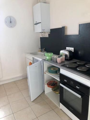 Il comprend une cuisine équipée d'une cuisinière et d'un réfrigérateur blanc. dans l'établissement Appartement Les Bons Vivants au coeur de Perrigny, à Perrigny-sur-Loire