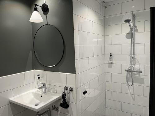 a bathroom with a sink and a shower with a mirror at Hotell Carl Friman in Motala