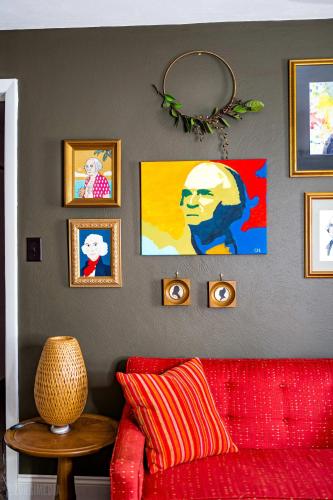a living room with a red couch and pictures on the wall at The George Washington on Mt Washington in Pittsburgh
