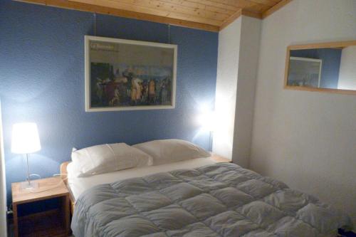 een bed in een slaapkamer met een blauwe muur bij Appartement confortable, 6 personnes, 2 chambres, 1 mezzanine - BLD2 in Beaufort