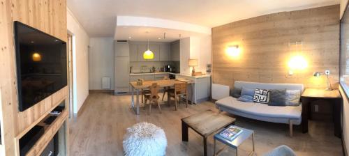 ein Wohnzimmer und eine Küche mit einem Sofa und einem Tisch in der Unterkunft Appartement centre village rénové, 6 personnes, 2 chambres - CL2D in Beaufort