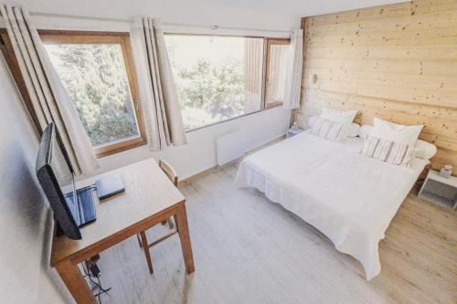 Schlafzimmer mit einem Bett und einem Schreibtisch mit einem TV in der Unterkunft Appartement centre village rénové, 6 personnes, 2 chambres - CL2D in Beaufort