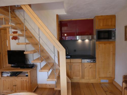 une cuisine avec un escalier, un four micro-ondes et une télévision dans l'établissement Appartement pied des pistes, 6 personnes, 3 chambres - EN14, à Beaufort
