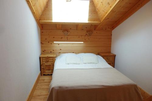 un lit dans une chambre avec un plafond en bois dans l'établissement Appartement spacieux, 8 personnes, 3 chambres, 1 mezzanine - ISALINE11, à Beaufort