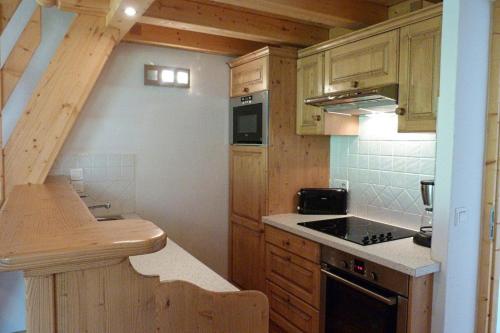une cuisine avec des armoires en bois et un four à plaques de cuisson dans l'établissement Appartement spacieux, 8 personnes, 3 chambres, 1 mezzanine - ISALINE11, à Beaufort