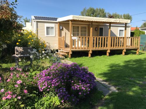 una pequeña casa con terraza y flores en Camping et Gîte La Garenne de moncourt baie somme, en Rue