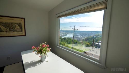 a window with a vase of flowers on a table at The Peak Mt Washington - Large 2bd Apt w A View in Pittsburgh