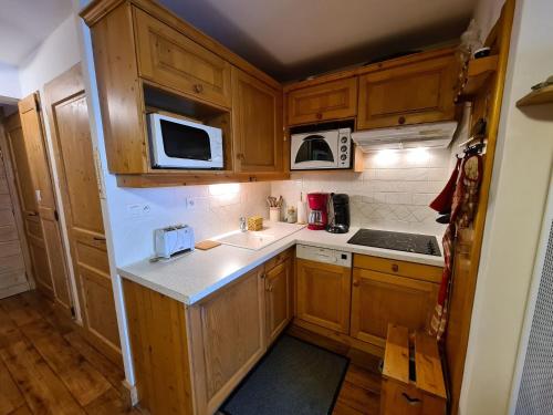 - une petite cuisine avec des placards en bois et des appareils blancs dans l'établissement Appartement confortable, 4 personnes, 1 chambre, 1 coin montagne - ALPINA03, à Beaufort