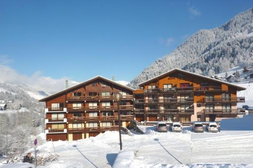 un grand bâtiment avec des voitures garées dans la neige dans l'établissement Appartement centre, 4 personnes, 1 chambre, 1 coin montagne - OPI12, à Beaufort