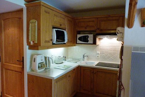 une cuisine avec des armoires en bois et un comptoir blanc dans l'établissement Appartement chaleureux, 4 personnes, 1 chambre, 1 coin montagne - ISALINE07, à Beaufort