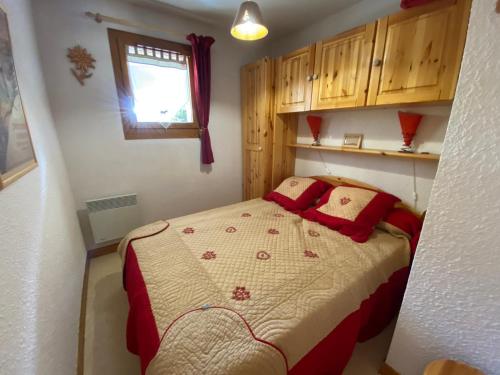 - une petite chambre avec un lit et des oreillers rouges dans l'établissement Appartement pied des pistes, 4 personnes, 1 chambre - MONT02, à Beaufort