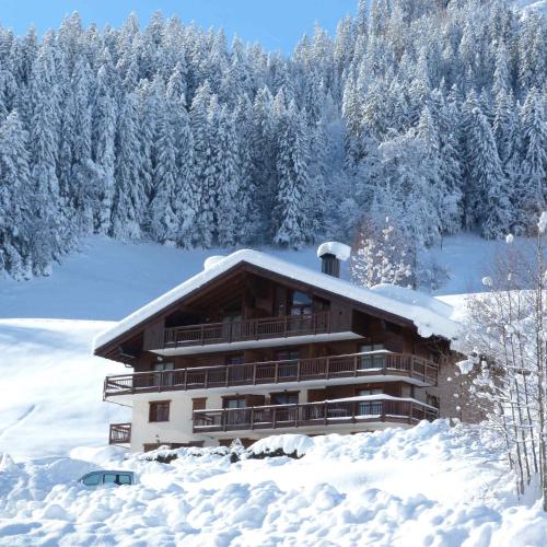 un bâtiment recouvert de neige avec des arbres en arrière-plan dans l'établissement Appartement jolie vue, 6 personnes, 2 chambres - HC04, à Beaufort