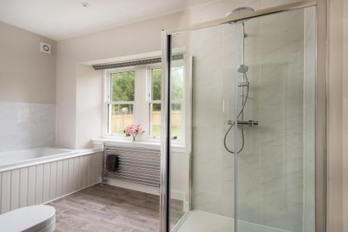 a bathroom with a shower and a toilet and a window at Coldwells Farmhouse in Dalkeith