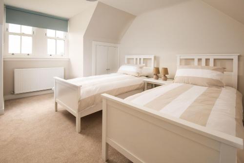 a white bedroom with two beds and a window at Coldwells Farmhouse in Dalkeith
