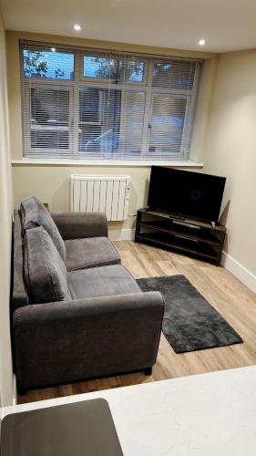 a living room with a couch and a flat screen tv at Abbey House in Horsham