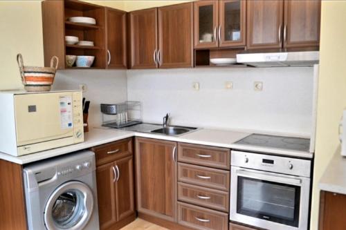 uma cozinha com armários de madeira e uma máquina de lavar e secar roupa em The Terrace Apartment em Stara Zagora